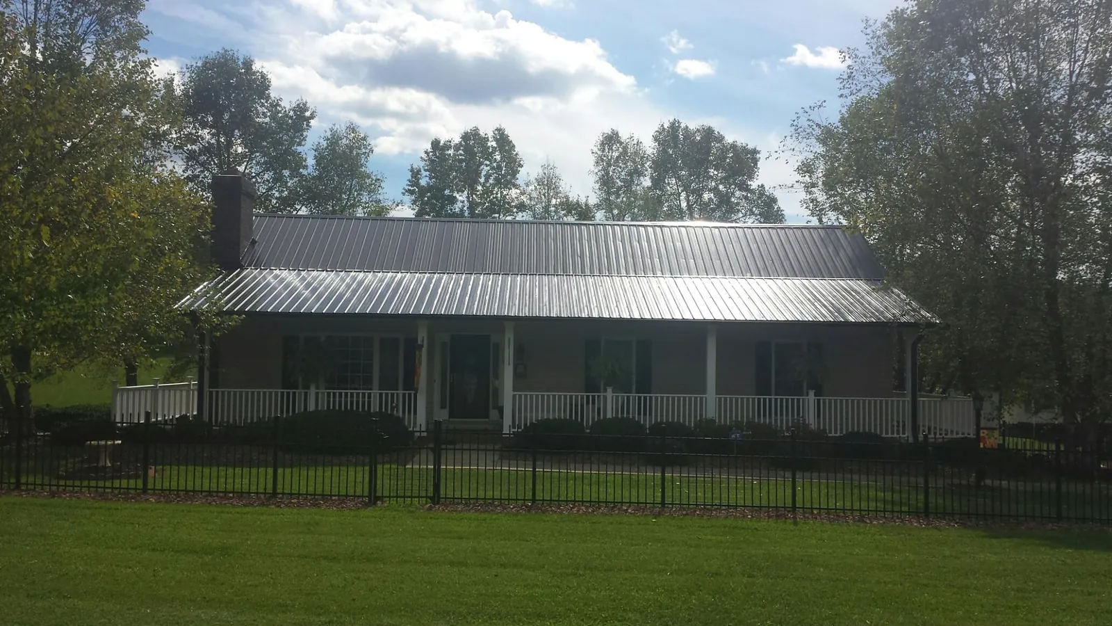 Gray metal roof on a brick ranch with a full width front porch — Gutter Guard Installation work by our crew in Mindoro