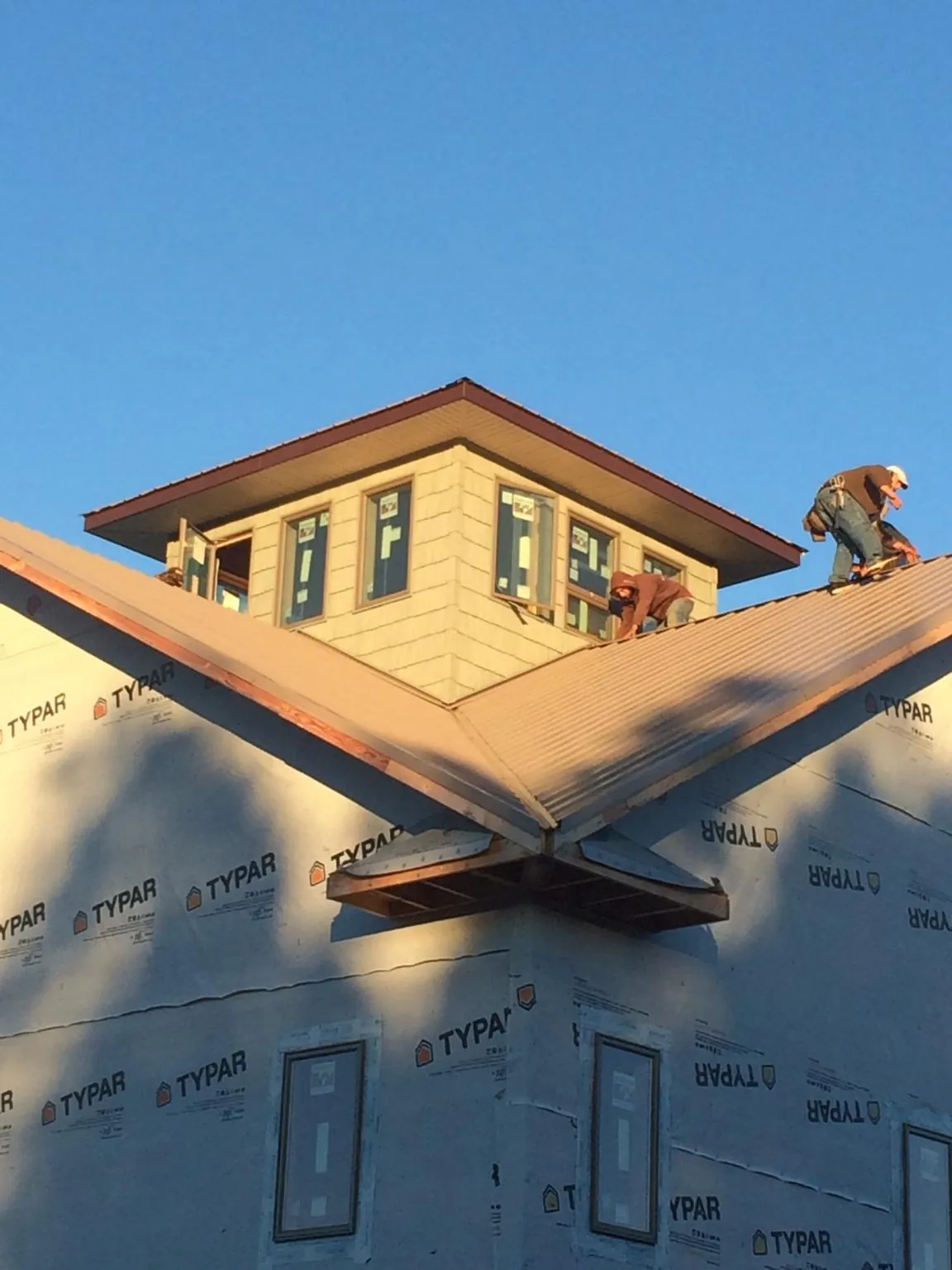 Roofers working around a rooftop cupola on a new metal roof at sunset — Roof Waterproofing in Mindoro by Roofing Brothers
